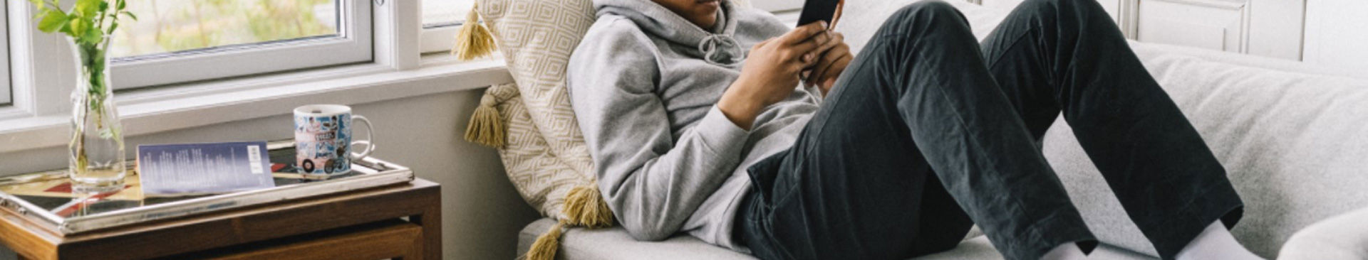 ung man ligger på soffa scrollar på mobilen