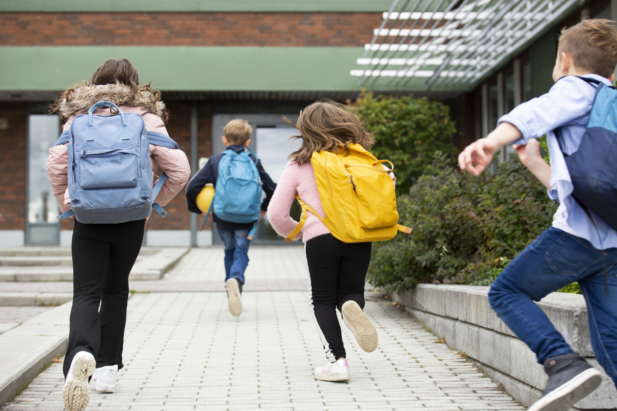 fyra barn med ryggsäckar springer till skolan
