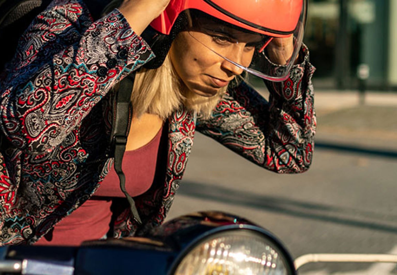 ung kvinna med röd hjälm vid sin moped