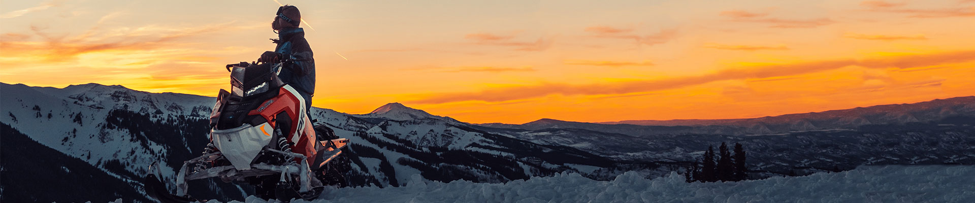 man vid sin snöskoter i solnedgång