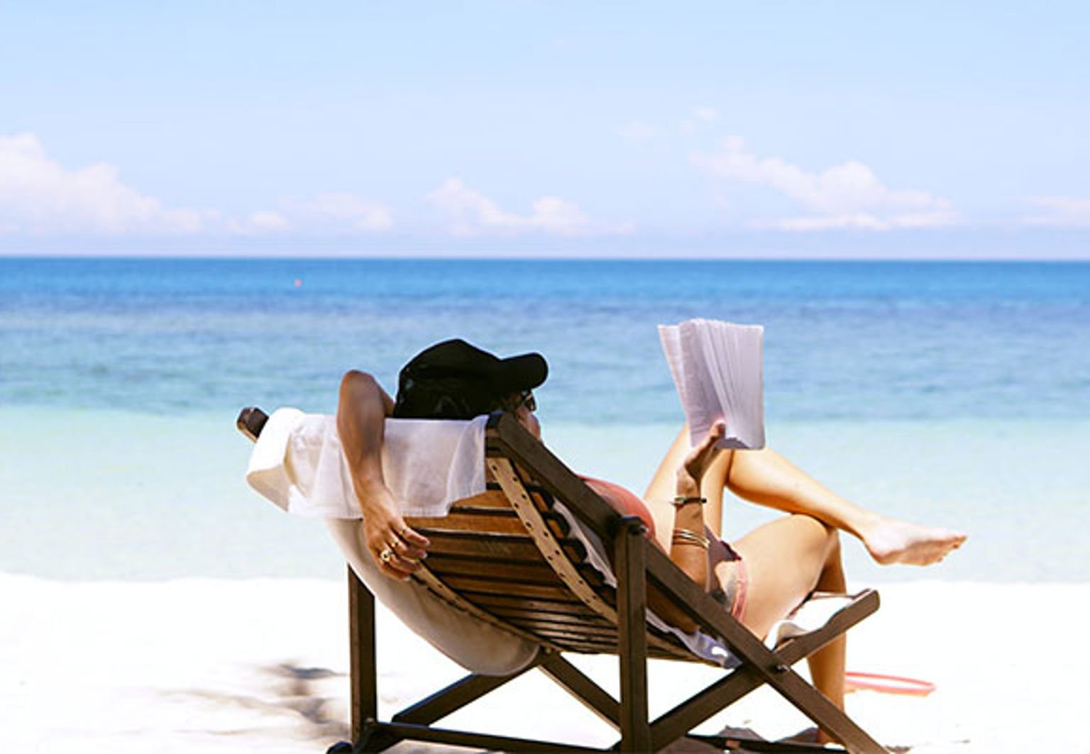 kvinna sitter i solstol på sandstrand