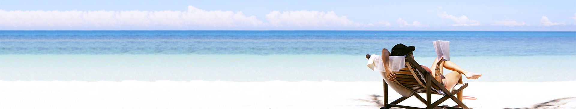 kvinna sitter i solstol på sandstrand