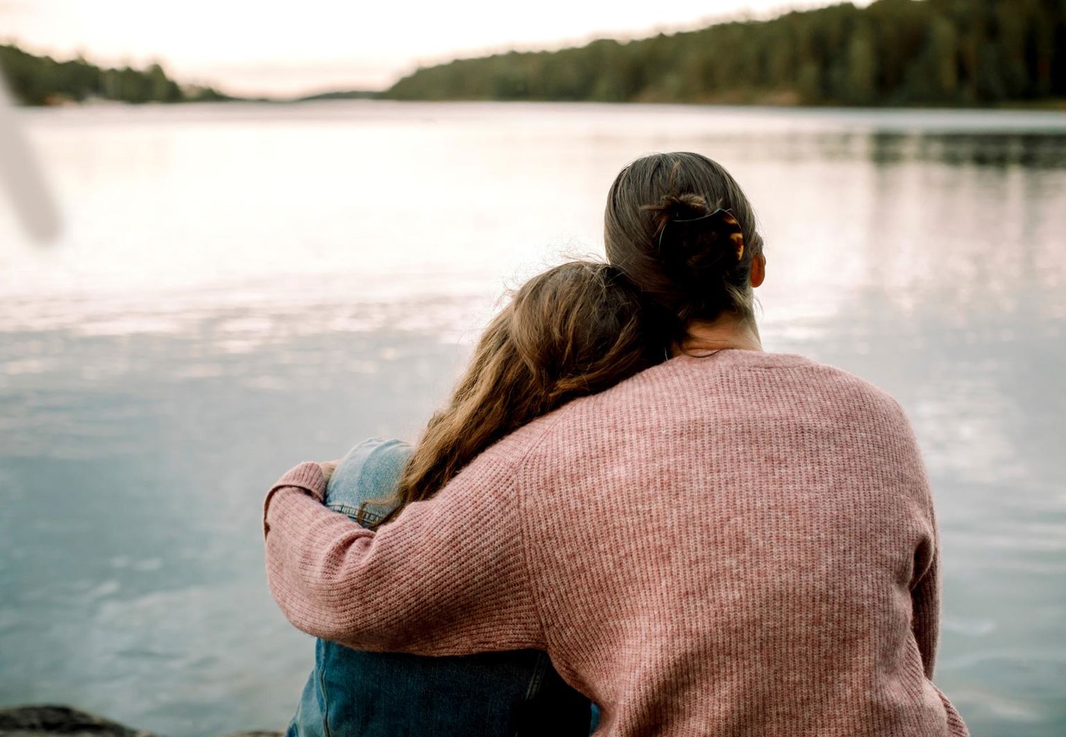 mamma håller om sin dotter vid en sjö