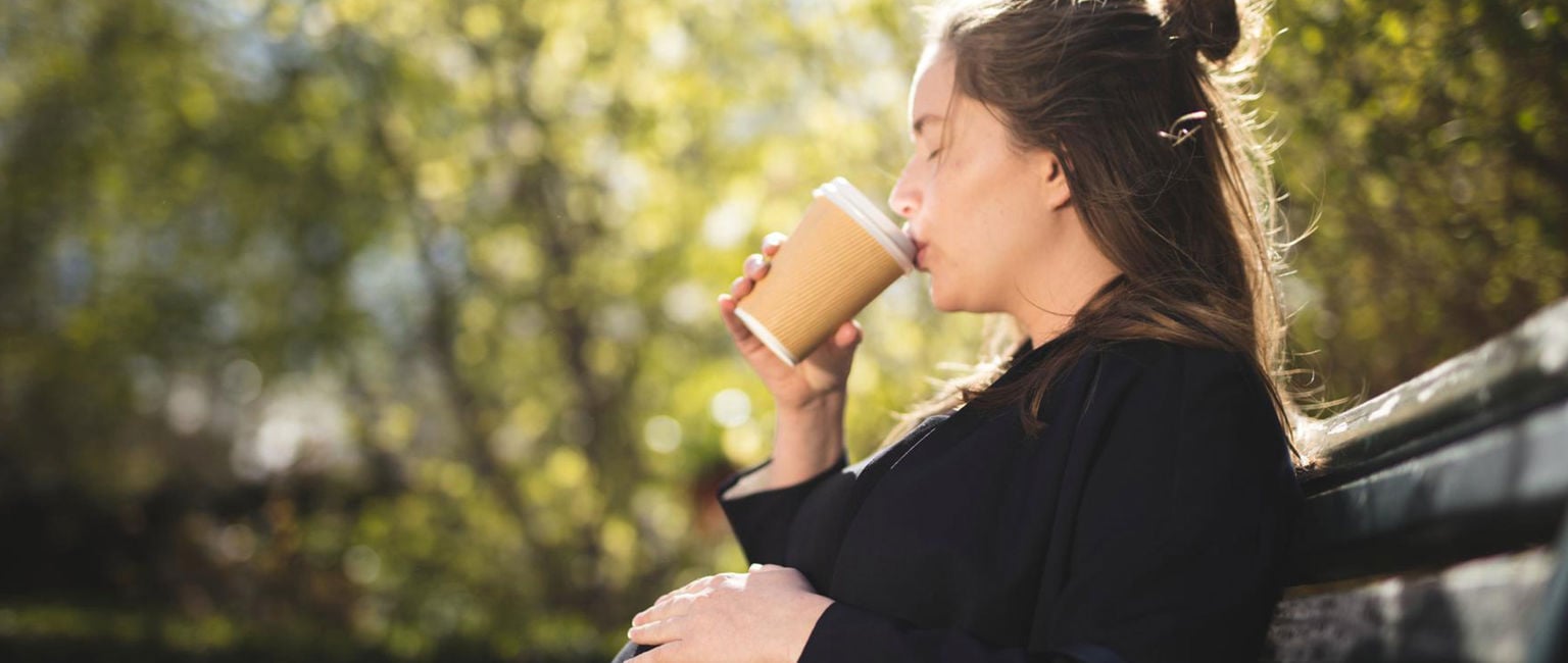 ung kvinna gravid på en parkbänk i solen