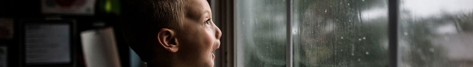 pojke tittar ut på stormen genom fönstret